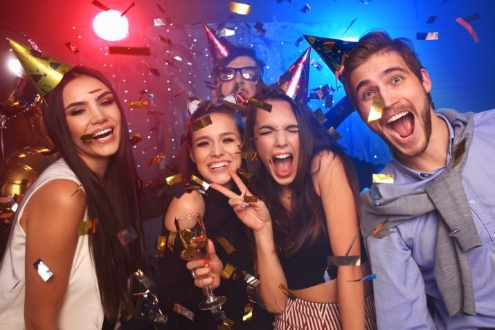 friends laugh and cheer at a colorful birthday party celebration