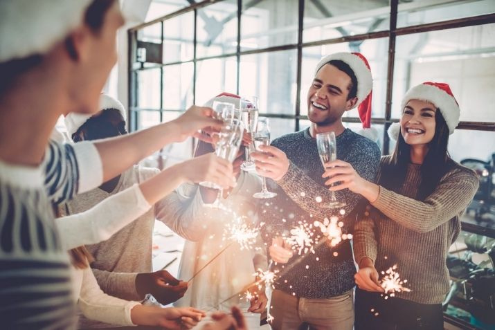 employees and coworkers celebrating a holiday christmas party in a modern office