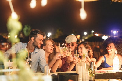 a group of friends toasting beers in an outdoor bar setting