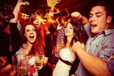 a group of friends dance in a dimly lit bar