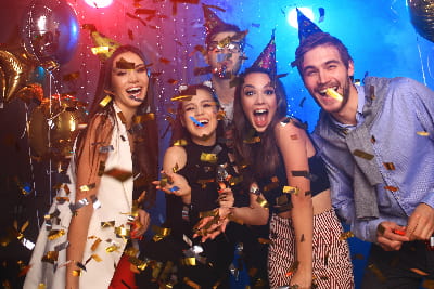 a group of friends dance in a dimly lit bar as confetti showers down